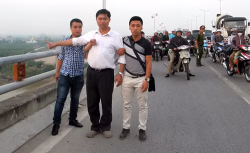 Ông Tường áo trắng (đứng giữa) được cơ quan CSĐT dẫn giải ra cầu Thanh Trì để thực nghiệm lại hiện trường