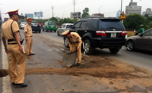 Dầu chảy lênh láng trên mặt đường khiến các chiến sĩ CSGT phải dùng cát đổ lên, để chống trơn trợt cho người đi đường.