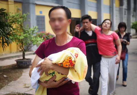 Người cha ngậm ngùi bế con trên tay, nước mắt chảy ngược trong lòng. Ảnh: Nguyễn Khánh - Tuổi trẻ.