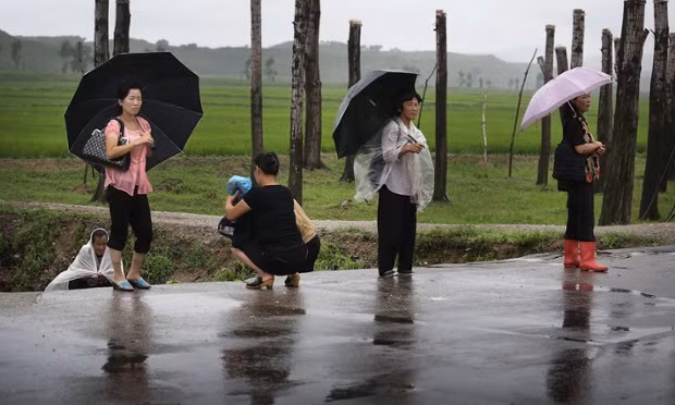 Người dân đứng chờ xe dưới trời mưa ở tỉnh Bắc Pyongan.