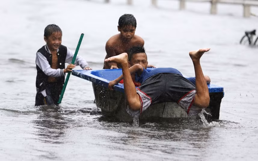 Trẻ em chơi với một bồn tắm trên đường phố ngập lụt ở ngoại ô Navotas.