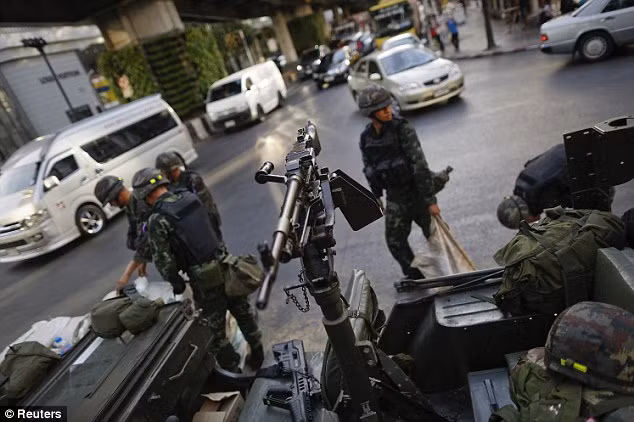 Các binh sĩ sử dụng những bao tải cát để gia cố một điểm chốt giữa ngã tư đường phố tại khu phố thương mại ở Bangkok.