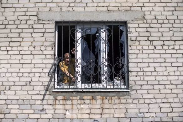 Người đàn ông nhìn ra ngoài cửa sổ kính bị vỡ.