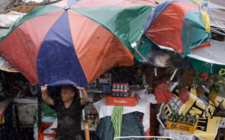 Người đàn ông giữ ô trước gió bão tại thành phố Taguig.