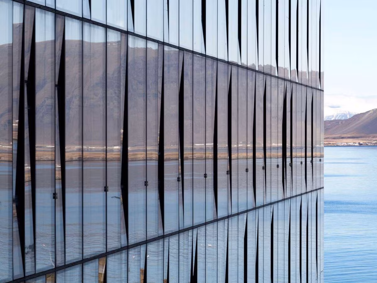 Tòa nhà Turninn ở Reykjavík, Iceland, với những tấm cửa sổ kính lớn in bóng phong cảnh xung quanh.