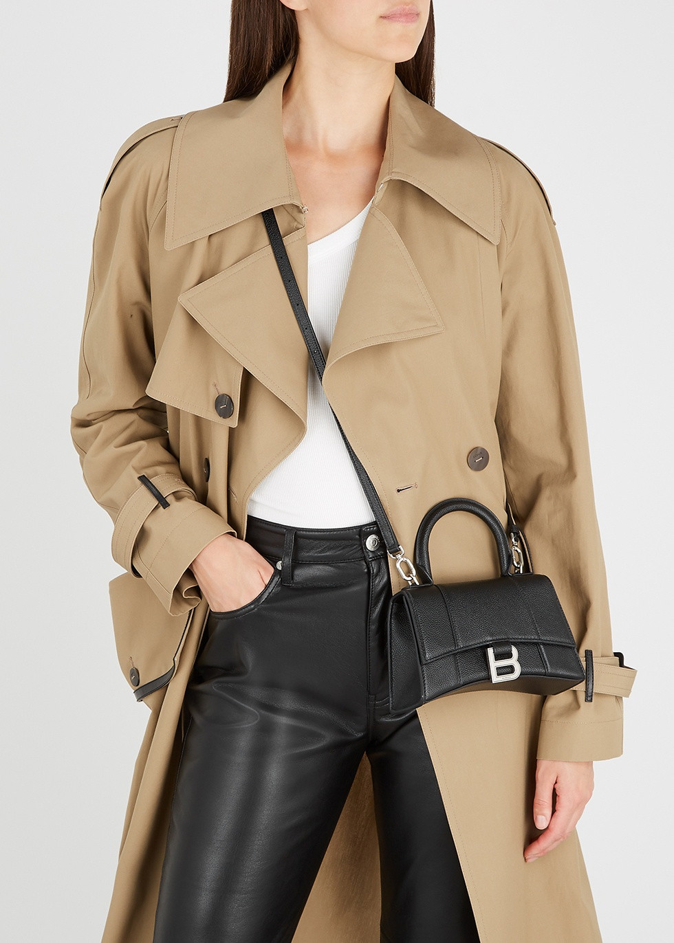  Balenciaga Hourglass XS Top Handle Bag (1.590 USD): Túi phối tông màu đen tối giản, phía trước gắn kết phụ kiện chữ B bằng kim loại sang trọng. Ngoài sử dụng theo cách cầm trên tay như trong ảnh, sản phẩm này còn trang bị thêm dây quai để đeo trên vai hoặc đeo chéo qua người. Ảnh: Net-a-Porter, Harvey Nichols.