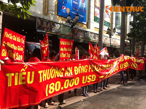 Hàng trăm tiểu thương tập trung trước mặt tiền trung tâm, trên tay cầm băng rôn với nội dung phản đối quy định tăng giá cho thuê.