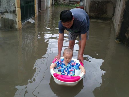Cho bé bơi thuyền mùa lũ.