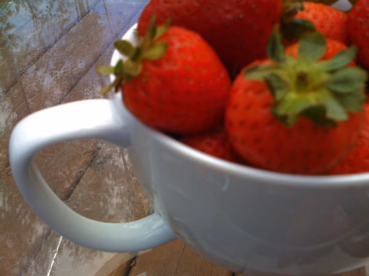 Bức hình chụp macro (chụp lại đối tượng với độ phóng đại cao, hoặc ít nhất thể hiện đúng kích thước của đối tượng chụp trong tương quan với kích thước của tấm film/sensor máy ảnh) một bát dâu tây bằng điện thoại iPhone đời đầu, cho thấy ánh sáng ảnh khá mờ, quả dâu tây không được bắt nét.