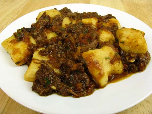 Nguyên liệu: (cho 4 người ăn):450 gr thịt bò bắp hoặc nạm, 1 củ hành khô, 1củ cà rốt, 1 nhánh cần tây, 15g nấm porcini (nếu có), 1 thanh quế, 3 lá đinh hương, Vài lá húng, 3 tép tỏi to, 1 thìa canh nước sốt cà chua, 250ml/1 cốc rượu vang đỏ, 400g cà chua, 1 thìa canh mứt cam, Rau mùi thái nhỏ, Muối, tiêu