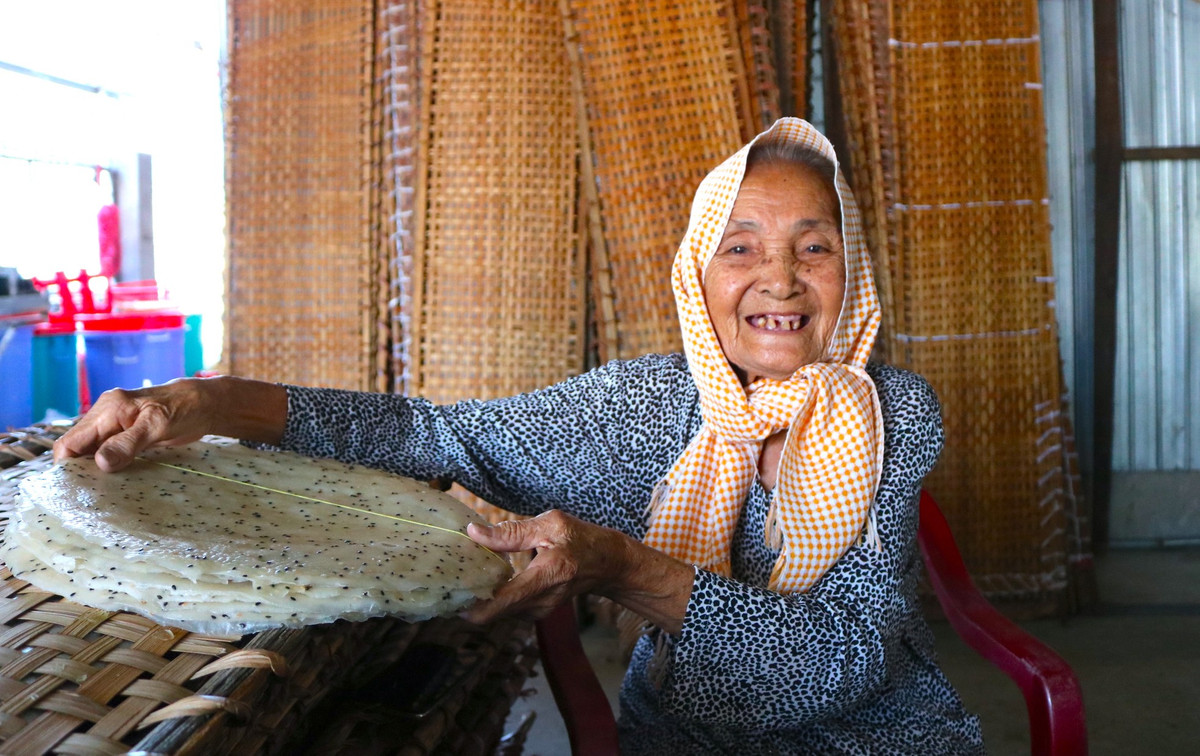 Có tuổi nghề hơn 30 năm, cụ Đỗ Thị Đượm (88 tuổi, ngụ phường Thuận Hưng) nhớ về những ngày khi mới khởi nghiệp nghề làm bánh tráng với nhiều thăng trầm. "Nghề này cực khổ lắm. Hồi đó, gia đình nghèo, tôi phải đi cắt lúa mướn, rồi ở lại mót lúa còn sót lại, bắt cá cạn để về làm mắm ăn. Sau đó, con dâu tôi mới dành dụm tiền xây được cái lò, rồi tôi và con gái cùng làm. Mấy chục năm trước tráng có cái Tết, mà chỉ tráng bánh tráng mặn thôi. Còn bây giờ tráng quanh năm, rồi con gái tôi mới tráng thêm bánh tráng lạt, bánh tráng ngọt và bánh tráng dừa. Nhu cầu của khách hàng ngày càng nhiều, gần đây nó đầu tư thêm máy tráng để kịp sản xuất cung ứng", cụ Đượm tâm sự - Ảnh: Kim Hà.