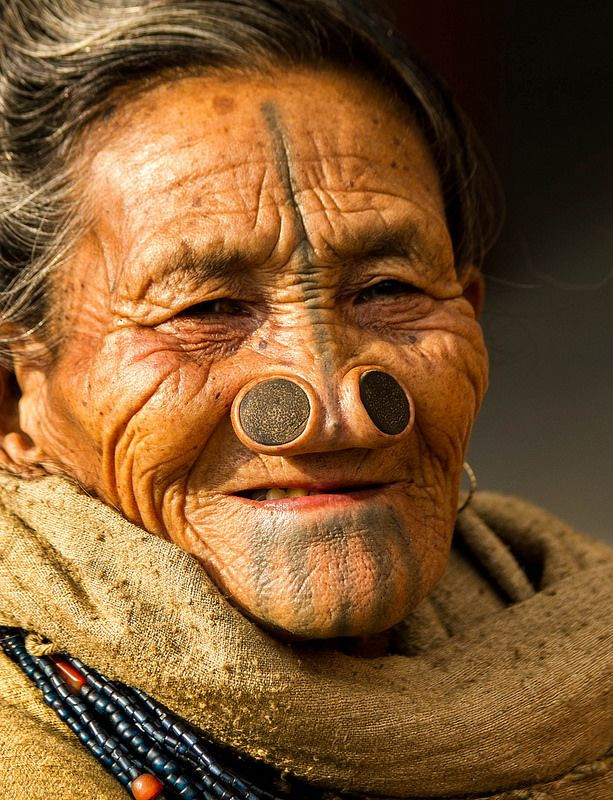  Bộ tộc Apatani (Ấn Độ) - Đeo nút mũi. Phụ nữ Apatani đeo nút mũi lớn từ nhỏ để làm cho mũi to hơn. Phong tục này bắt đầu từ thời cổ xưa để làm giảm sức hấp dẫn của phụ nữ trước các bộ tộc khác nhằm tránh bị bắt cóc. Ảnh: Pinterest.