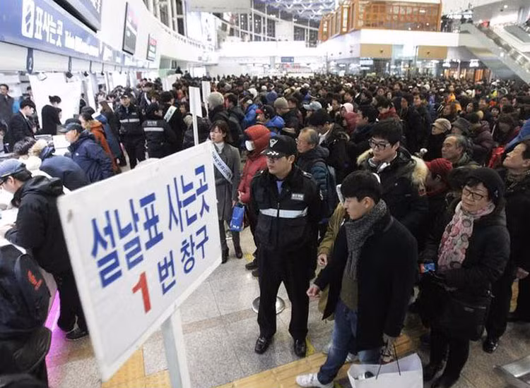 Trong khi đó, người dân Hàn Quốc cũng tất bật về quê. Mọi người đứng xếp chờ mua vé tàu ở Ga xe lửa Seoul hôm 8/1.