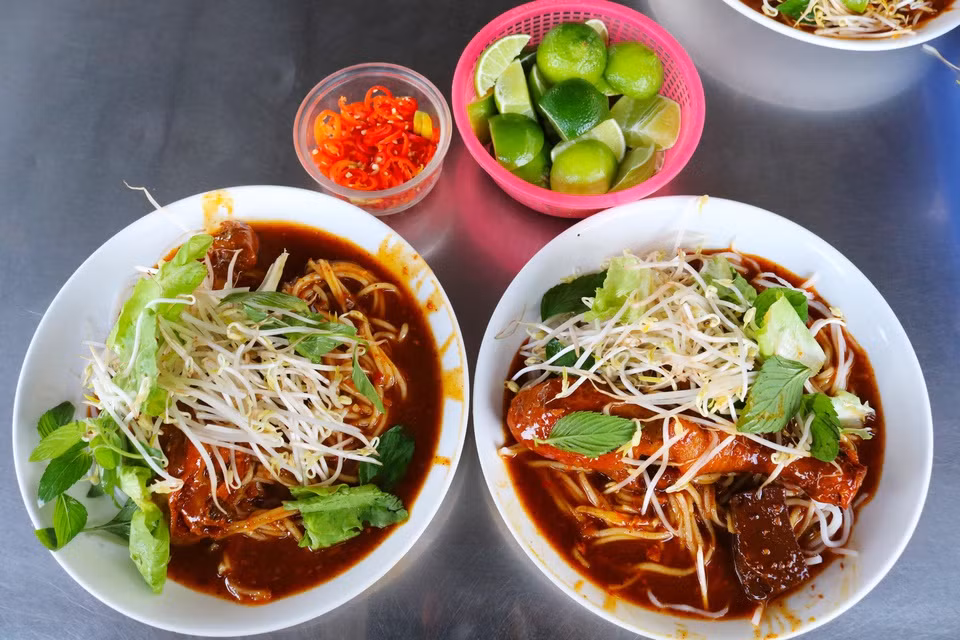 br/> Bánh tầm cay: Bánh tầm còn được gọi là bánh tằm, do sợi bánh có hình dạng như những con tằm. Mỗi mẻ bánh phải trải qua nhiều công đoạn sơ chế, chế biến như chọn gạo, xay thành bột, hồ gạo, xe sợi... Sau khi làm xong sợi bánh, đầu bếp sẽ thêm các nguyên liệu khác như xíu mại, thịt nướng, cà ri hay tàu hũ ky để tô điểm hương vị cho món ăn. Vị ngọt béo và hơi cay nơi đầu lưỡi của xíu mại hay thịt gà sẽ kích thích vị giác tối đa. Ảnh: camautourism