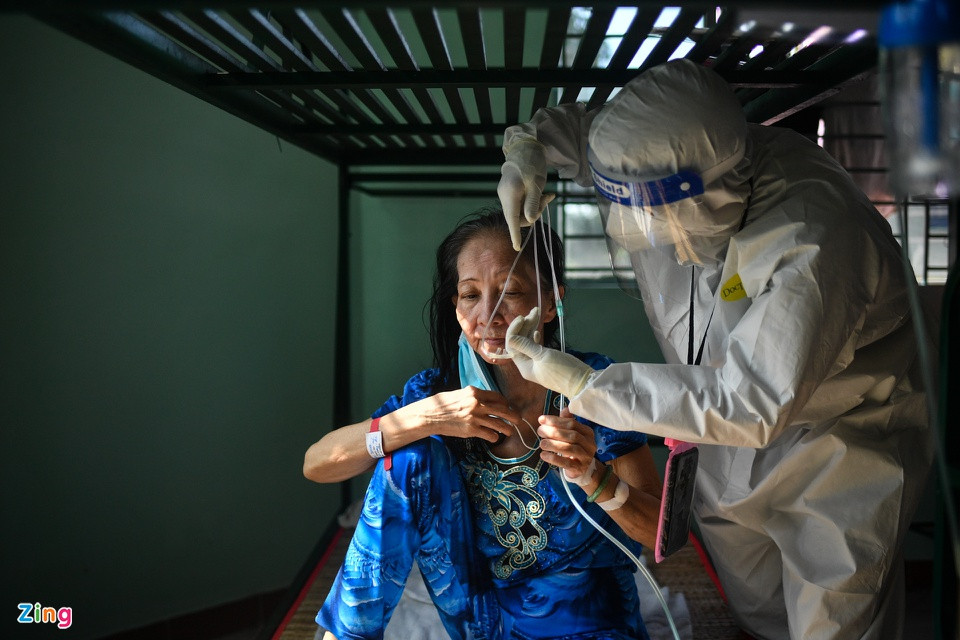 br/> Bác sĩ Đỗ Hiếu Trường Hải đeo oxy gọng cho một người phụ nữ sau khi bà có triệu chứng khó thở. Bác sĩ Hải là người phụ trách khu nhà 5 tầng thu dung bệnh nhân nhẹ. Tại đây có riêng 1 tầng để theo dõi những F0 lớn tuổi, có bệnh nền có thở oxy gọng.