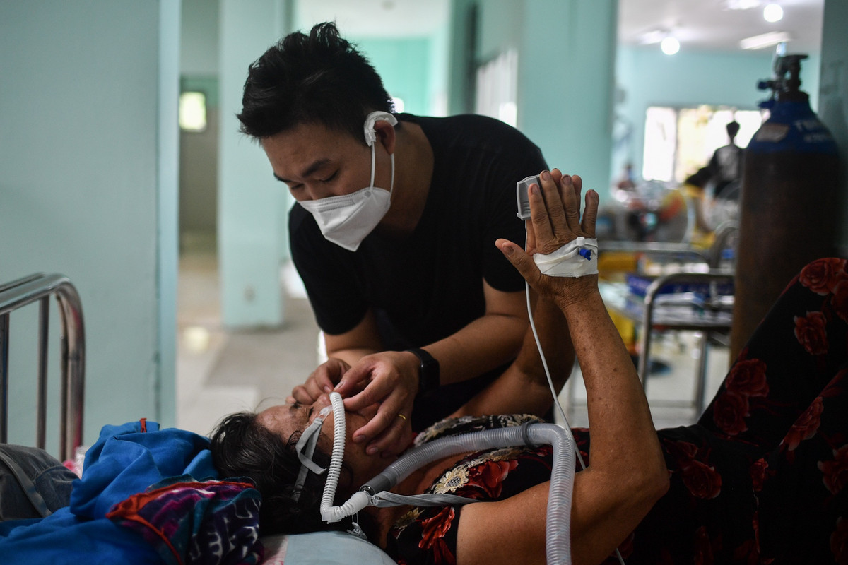 Trong phòng cấp cứu, anh Phạm Minh Tuấn đưa tay giữ chặt ống thở oxy dòng cao (HFNC) vào mũi mẹ. Mẹ anh đột nhiên trở nặng, thở oxy mask không đáp ứng, SpO2 có lúc ở mức 80%.