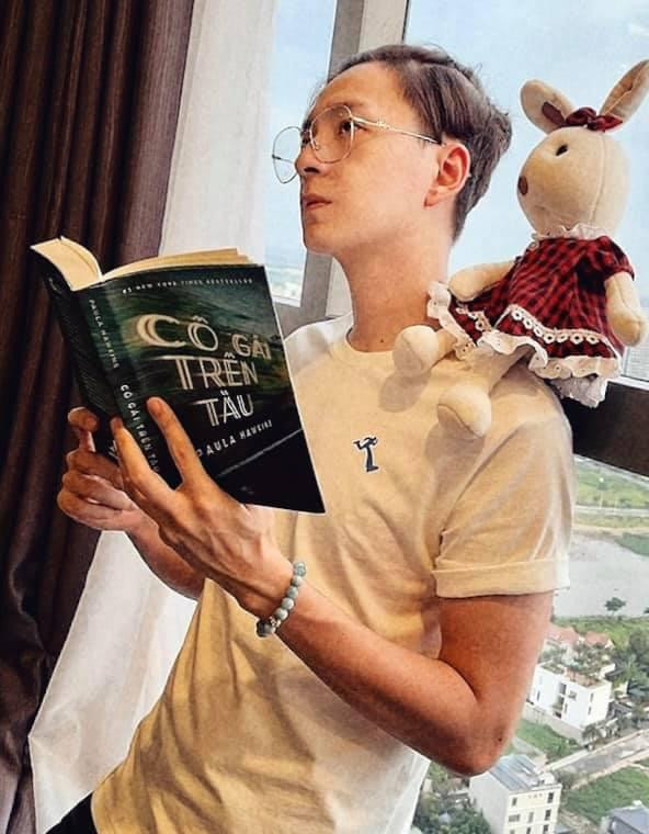 ọc cuốn sách "Cô Gái Trên Tàu" và nhìn thật xa xôi.