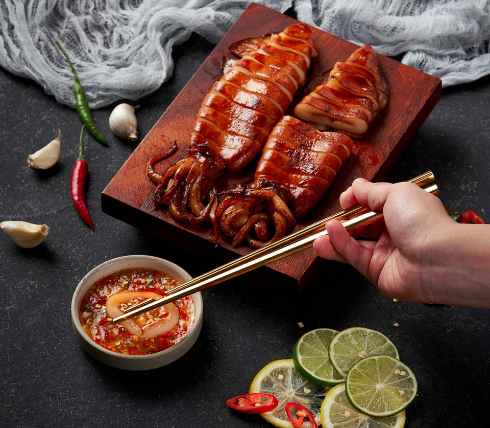 br/> Mực nướng sốt Thái còn có tên gọi là pla muek yang, món ăn thường xuất hiện trên đường phố Thái Lan. Sốt chua ngọt cay của Thái có thể tìm thấy trong các siêu thị hoặc dễ dàng tự làm với các nguyên liệu như nước cốt chanh, nước mắm, ớt, rau mùi, đường, tỏi. Người Thái Lan ăn mực nướng kèm đậu phộng và rau mùi. Các khoanh mực ống tươi, giòn có thể dùng như món chính, món khai vị hoặc trộn với salad tùy khẩu vị của gia đình bạn. Ảnh: Kin Hoi.