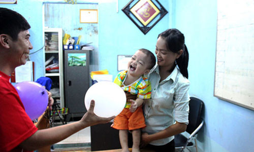 Bé trai vui đùa với cán bộ phường. (Ảnh: Hải Hiếu)