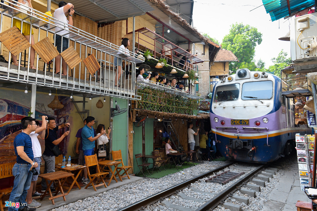Du khách đứng gọn vào hai bên đường, lấy điện thoại, máy ảnh để ghi lại khoảnh khắc tàu đi qua. Một chủ quán cho biết khu vực này chưa xảy ra sự cố đáng tiếc nào.