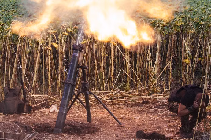 Một lính Ukraine che tai lại khi khai hỏa một quả đạn pháo.