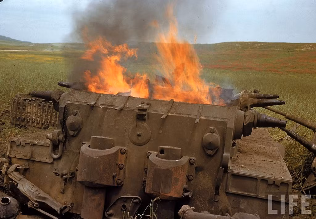 Một chiếc xe tăng Đức vẫn còn bốc cháy nghi ngút ở gần đó.