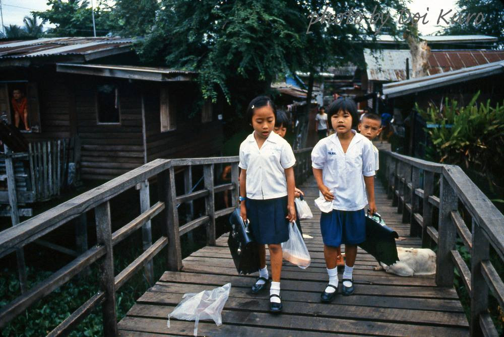 Học sinh đi qua cây cầu gỗ để đến trường.