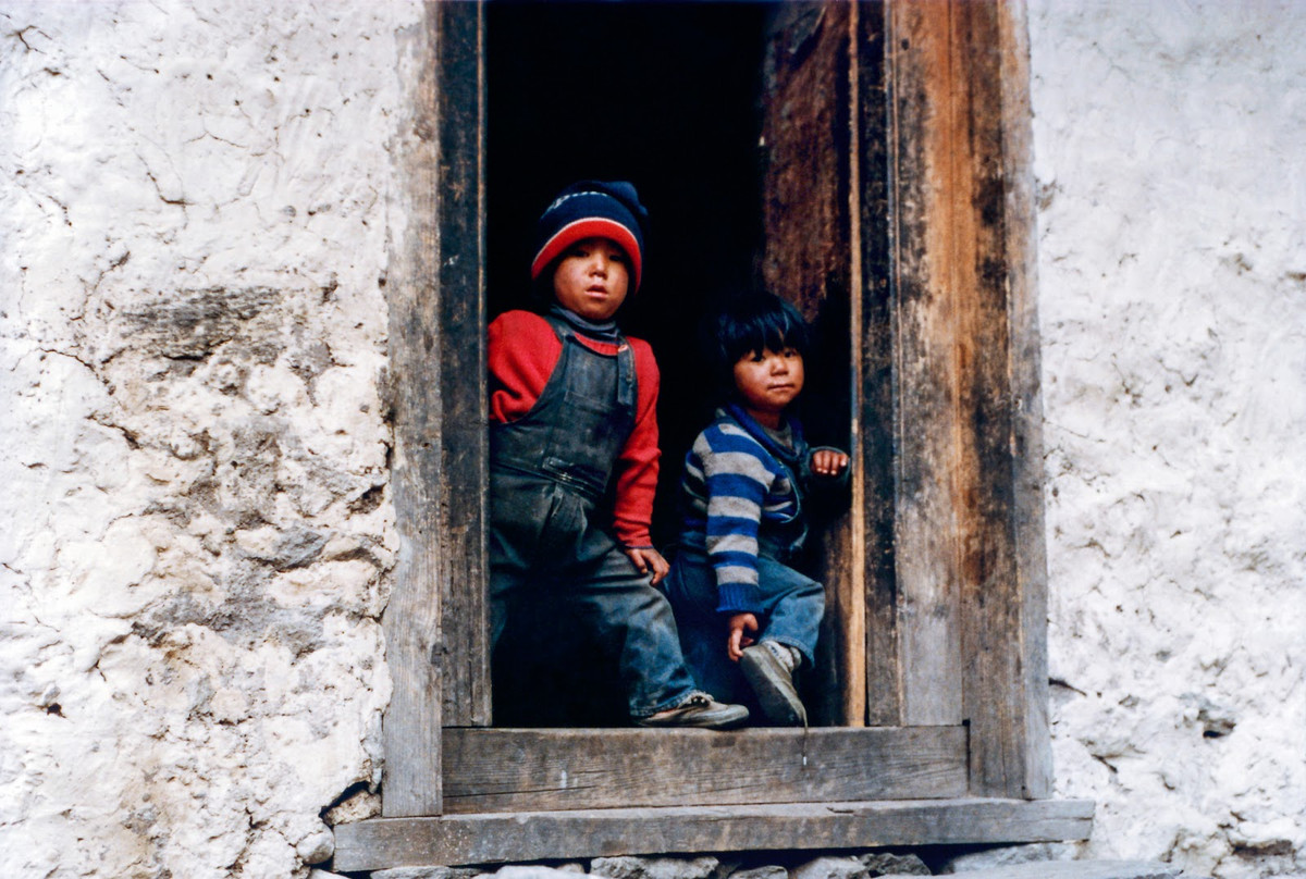 Hai em bé bên cửa nhà.