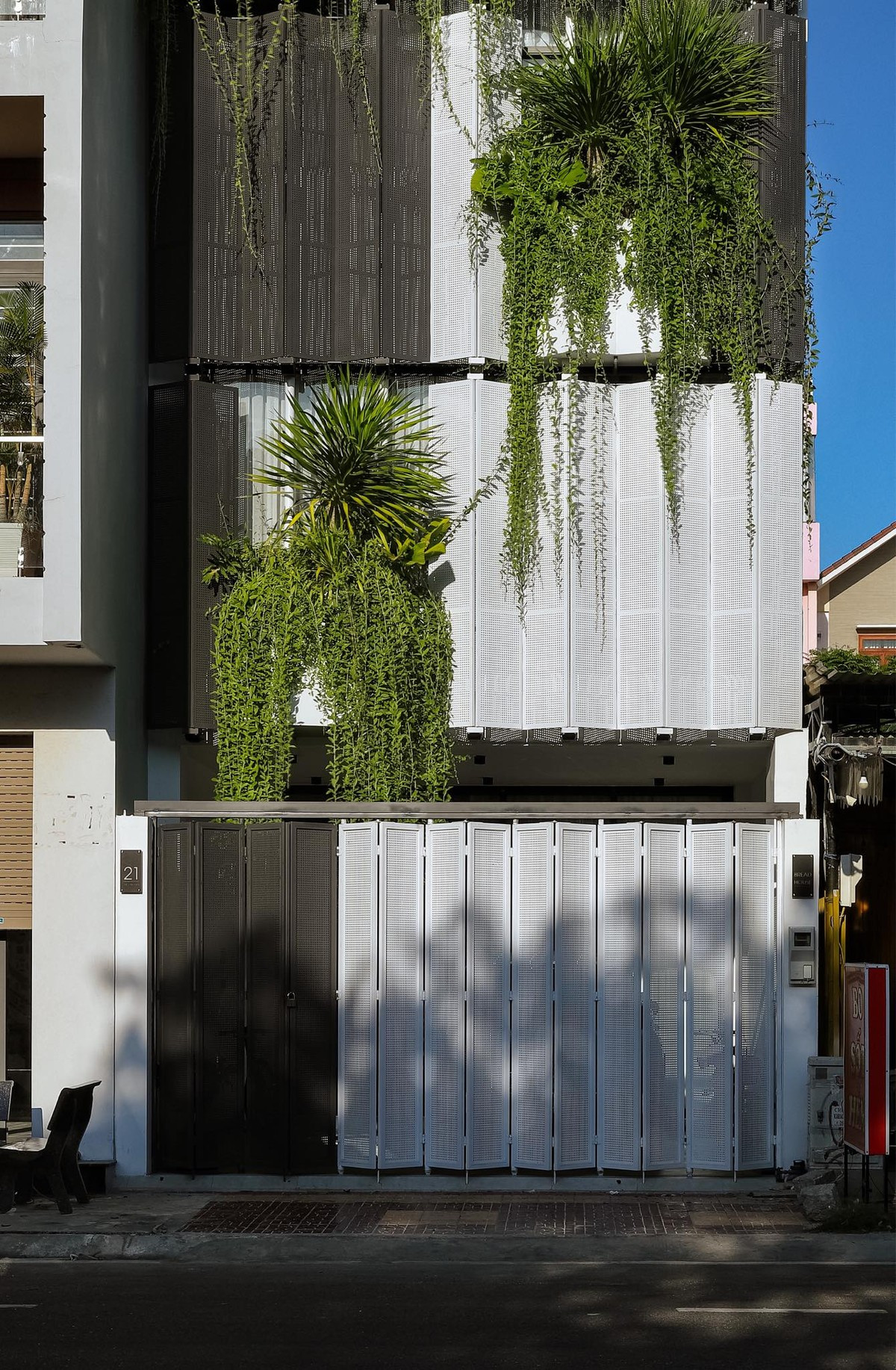 Mặt tiền công trình khoác trên mình lớp áo che phủ độc đáo, đan xen giữa những tấm kim loại và cây xanh ngập tràn.