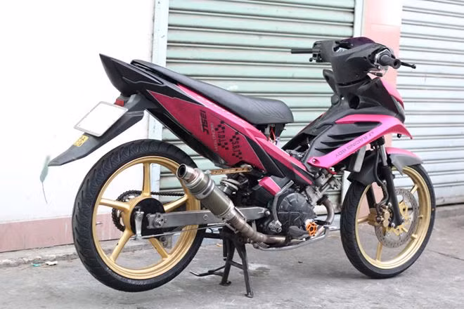 Phần đầu xe được độ lại với dàn vỏ của chiếc Yamaha Luvias trông khá ngầu. Cùng với đó là sự kết hợp giữa hai tông màu hồng đen, khá lạ mắt. Không chỉ thay đổi về kiểu dáng, động cơ của chiếc Exciter độ cũng được nâng công suất, kết hợp cùng bộ ống xả AHM.