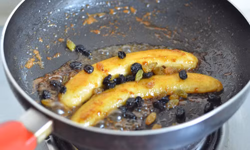 Bước 6: Bạn đổ nho khô được ngâm với rượu rum vào chảo.