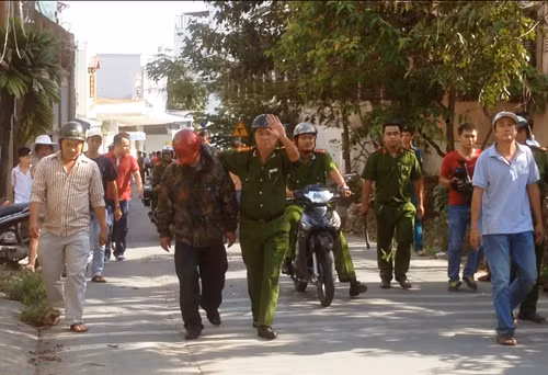 Thượng tá Sâm (bìa phải) đang "dìu" tên Long (đội mũ BH đỏ) rời khỏi hiện trường, đưa ra xe về trụ sở công an quận 9 để lập hồ sơ xử lý.