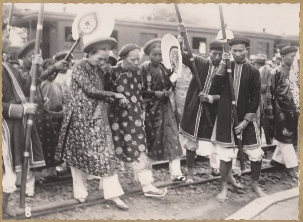 Hình này được chụp khi Bà Nguyễn Hữu Thị Nhàn đã cao tuổi, đang được hai cung nhân dìu đỡ tại một nhà ga xe lửa.