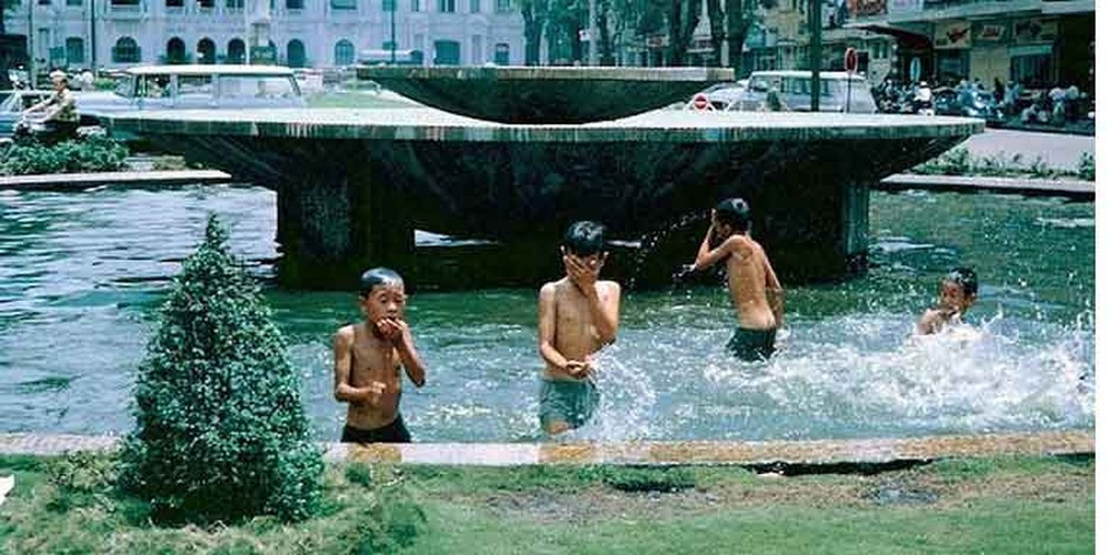 Trẻ em bơi lội tại đài phun nước giữa giao lộ Nguyễn Huệ - Lê Lợi (vòng xoay Cây Liễu), Sài Gòn năm 1967. Ảnh: Bill Mullin.