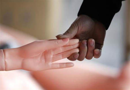 Một kỹ thuật viên nắm tay búp bê để thử cảm giác thật.