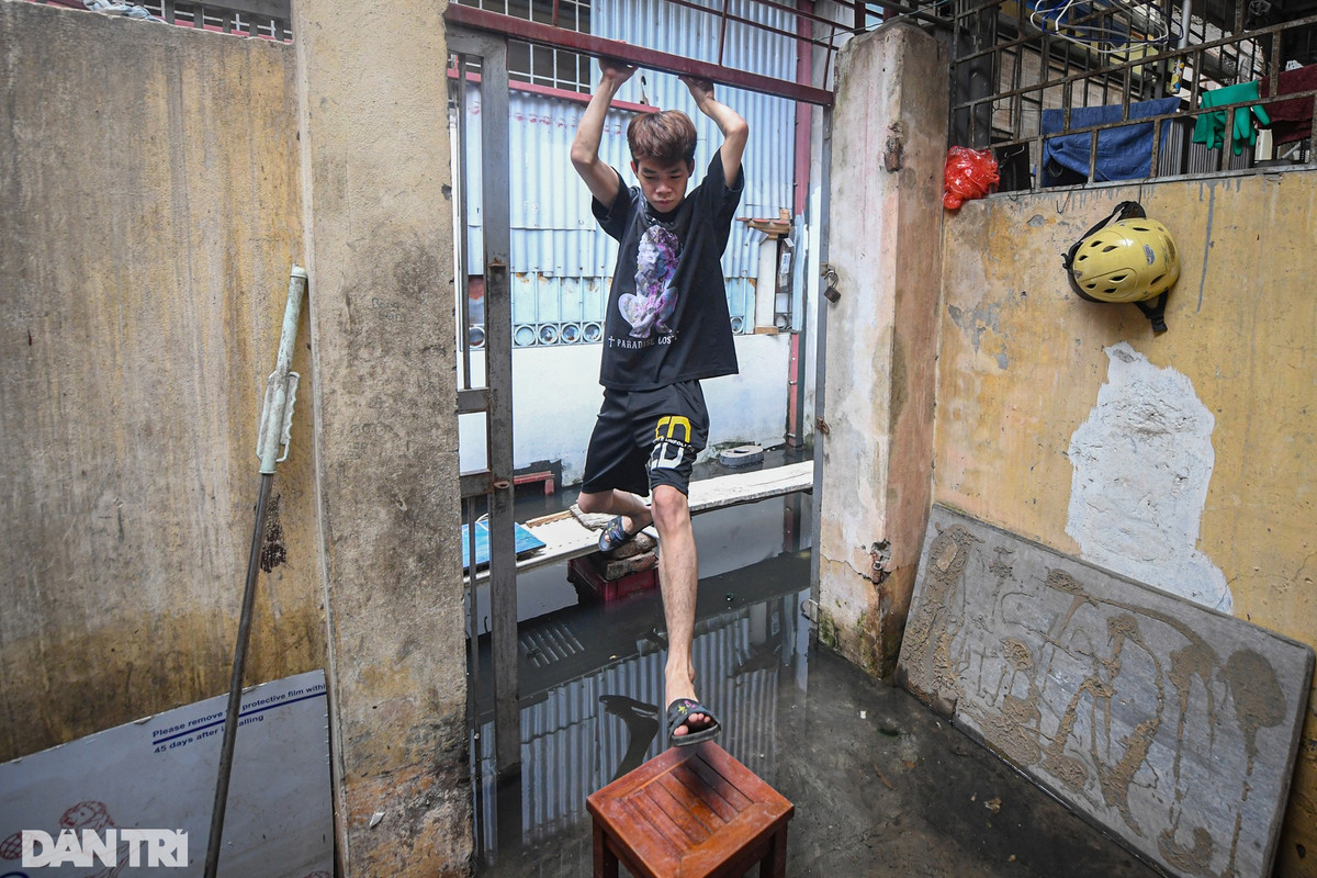 Một bạn trẻ sống trong ngõ 91 Âu Cơ đã phải bắc ghế tạo lối đi từ cầu khỉ để có thể vào được nhà khi bên dưới là dòng nước ô nhiễm.