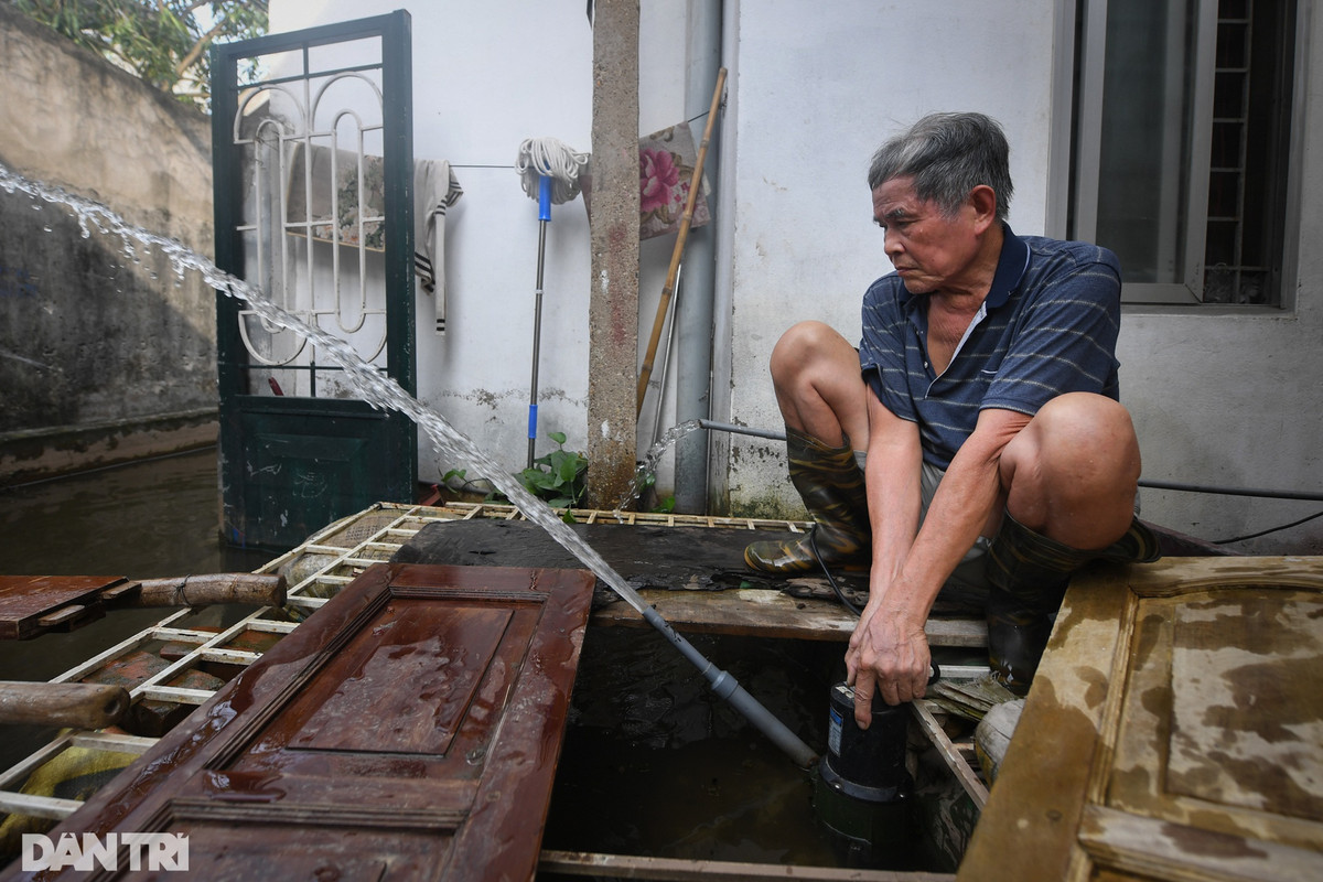 Ông Phan Hữu Cường, Phó tổ trưởng tổ 12 phường Tứ Liên trên tay chiếc máy bơm hoạt động hết công suất để đẩy nước quay ngược lại ngõ cứu lấy đồ đạc trong nhà.