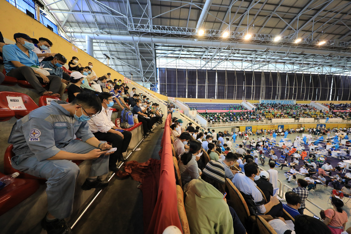 Bên trong nhà thi đấu Phú Thọ, hàng trăm người dân ngồi trên các khán đài, chờ tới lượt khám sàng lọc và tiêm vaccine.