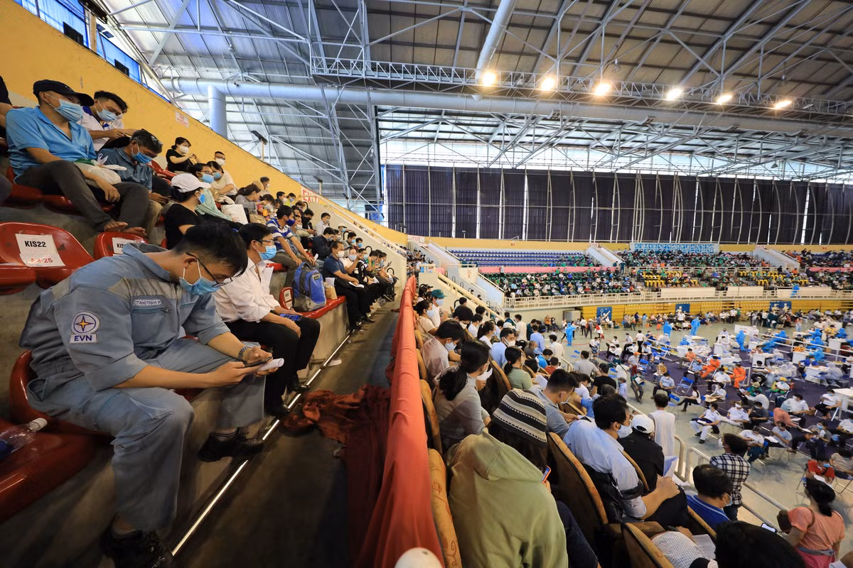Bên trong nhà thi đấu Phú Thọ, hàng trăm người dân ngồi trên các khán đài, chờ tới lượt khám sàng lọc và tiêm vaccine.