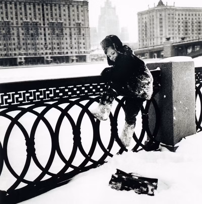Em bé Liên Xô hồn nhiên, vui đùa trên tuyết, tinh nghịch trèo lên lan can.