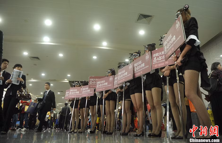 Những cô gái "chân dài" trong bộ đồ ngắn cầm những tấm áp phích quảng cáo cho một công ty bất động sản tại hội chợ nhà ở được tổ chức tại Trùng Khánh, Trung Quốc vào ngày 17/10.