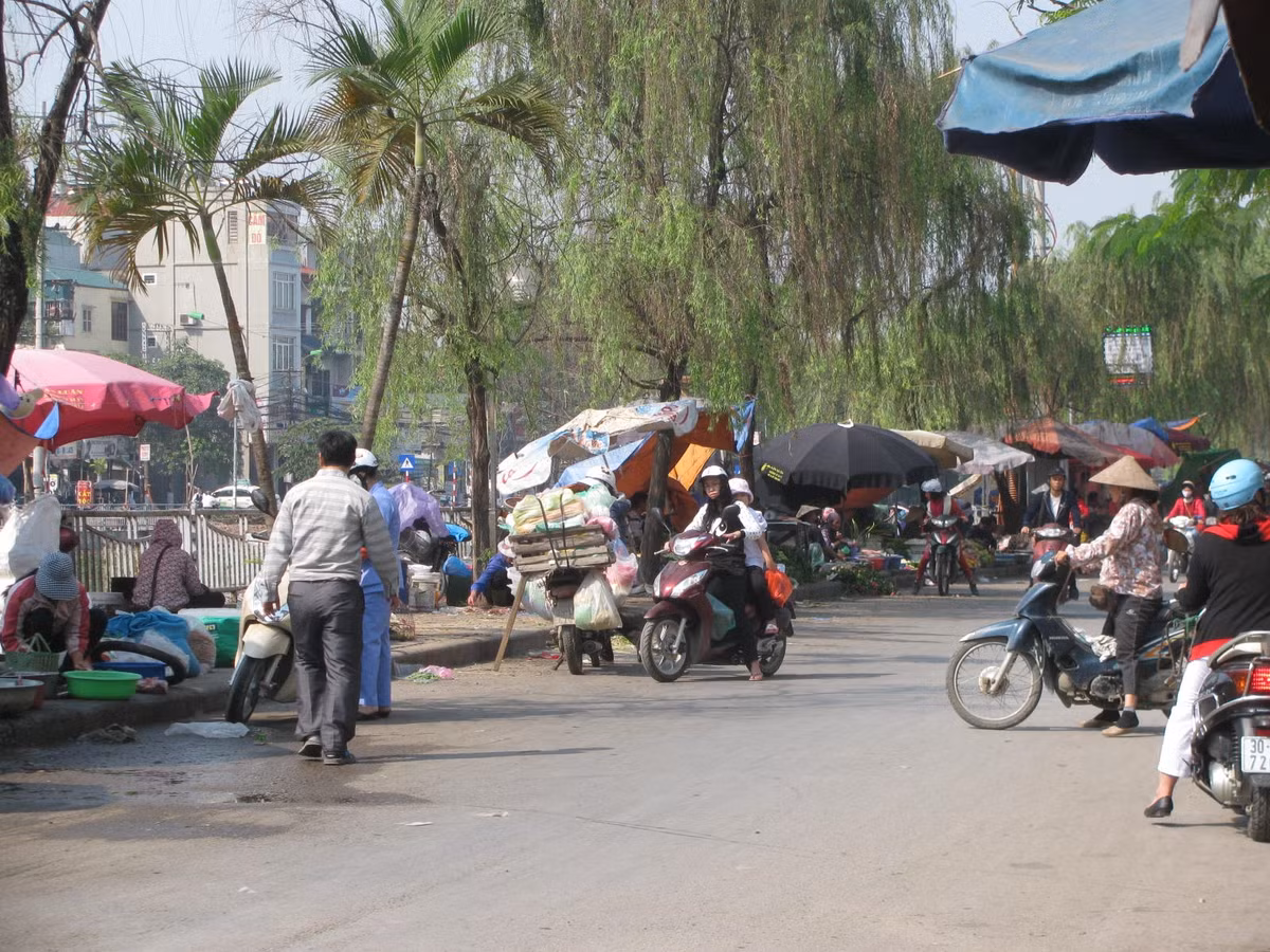 Chỉ cần người kinh doanh trải vài tấm ni lông trên vỉa hè đường phố bày bán các mặt hàng là có thể biến thành chợ. Người mua túm tụm xung quanh khiến lòng đường trở nên chật kín, cản trở các phương tiện đi lại. Trong ảnh là chợ họp trên vỉa hè đường Khương Hạ Mới (quận Thanh Xuân).