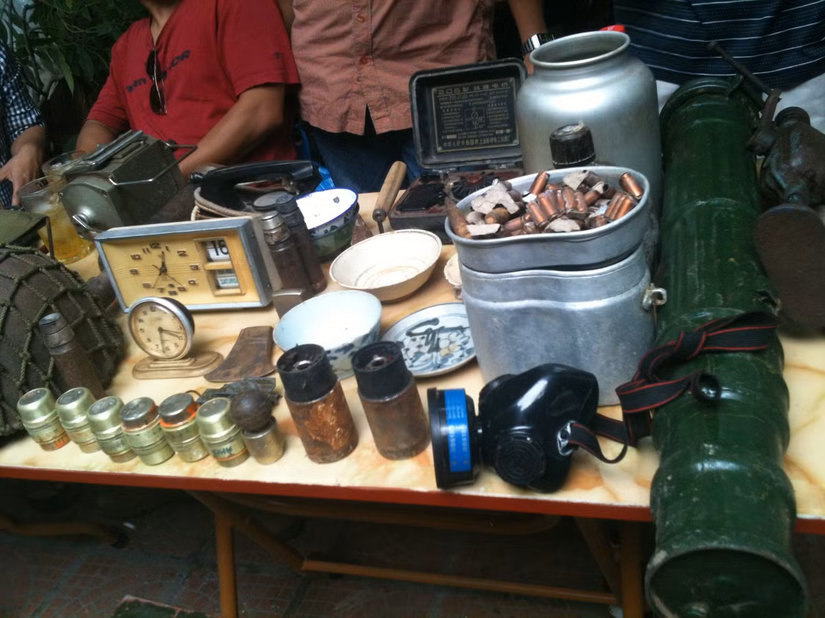 Nhiều người đến với phiên chợ đồ xưa mong muốn tìm lại những món đồ gắn bó với một thời kỳ lịch sử của dân tộc mà bản thân họ là nhân chứng sống của thời kỳ đó. Trong ảnh là một gian hàng bày bán những kỉ vật thời chiến tranh như: gi-đông, mũ cối, đầu đạn...