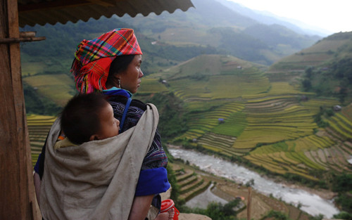 Hai mẹ con người H'Mông cùng nhìn về phía xa với những thửa ruộng bậc thang trải rộng bạt ngàn.