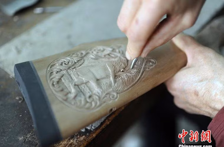 Một công nhân đang chạm khắc hoa văn trên báng súng có thể là loại súng săn dành cho thị trường dân sự.