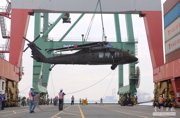 Chiếc trực thăng UH-60 Black Hawk đang được các nhân viên di chuyển xuống cảng.