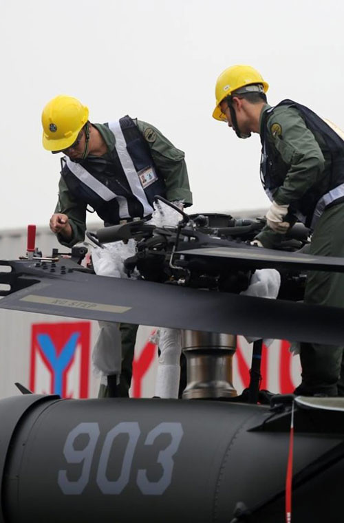 Các nhân viên đang tiến hành dỡ và lắp ráp bộ phận cánh của trực thăng UH-60 Black Hawk tại cảng Cao Hùng.