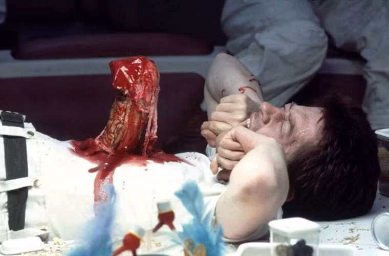 Người ngoài hành tinh (Alien, 1979) - Nhân vật chính trong phim của đạo diễn Ridley Scott là một loài vật ghê rợn ngoài hình tinh sinh sôi trong vật chủ là phi hành gia Kane (John Hurt thủ vai). Kane là người phát hiện ra ổ trứng của loài vật này trên hành tinh nhỏ LV-426, khi một quả trứng bị vỡ, một sinh vật nhảy ra, đập kính bảo vệ và bám vào mặt Kane. Anh ngã ra bất tỉnh nhưng vài giờ sau, lúc tỉnh lại, anh trải qua cơn đau ngực dữ dội và đó là lúc con vật ký sinh trong cơ thể anh bung ra từ lồng ngực.