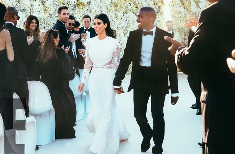 Cô dâu Kim Kardashian duyên dáng trong chiếc váy ren trắng được Givenchy Haute Couture thiết kế riêng. Bên cạnh chú rể Kanye West lịch lãm trong bộ vest tối màu cùng thương hiệu với váy cô dâu.