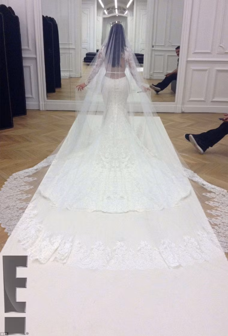 Chiếc váy hở lưng, dài tay kiểu đuôi cá kết hợp với tấm voan cài đầu dài quết đất, mái tóc cô dâu không vấn mà xõa dài tự nhiên.